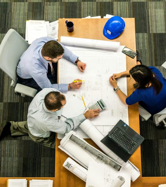 Top view of a team working on construction plans in an office setting.